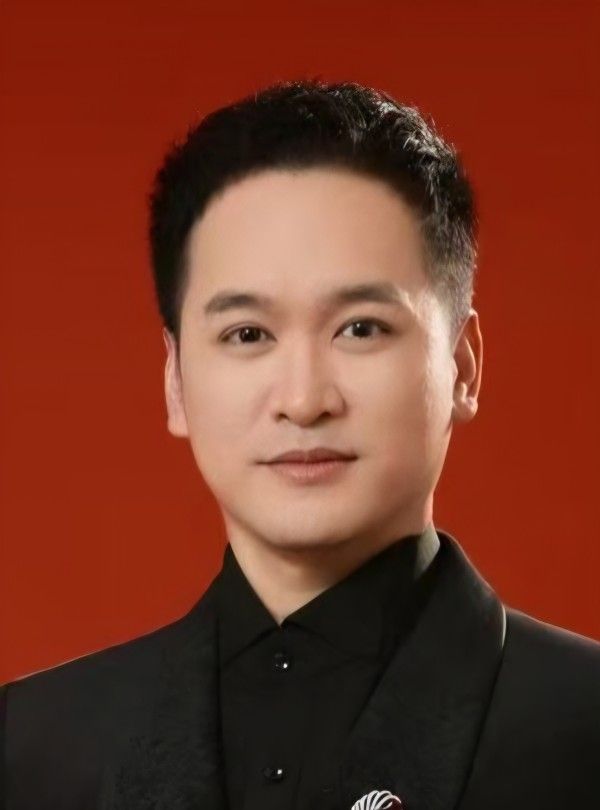 Portrait of James B., massage therapist at James Shiatsu Thai in Chiswick, in a black jacket against a red backdrop